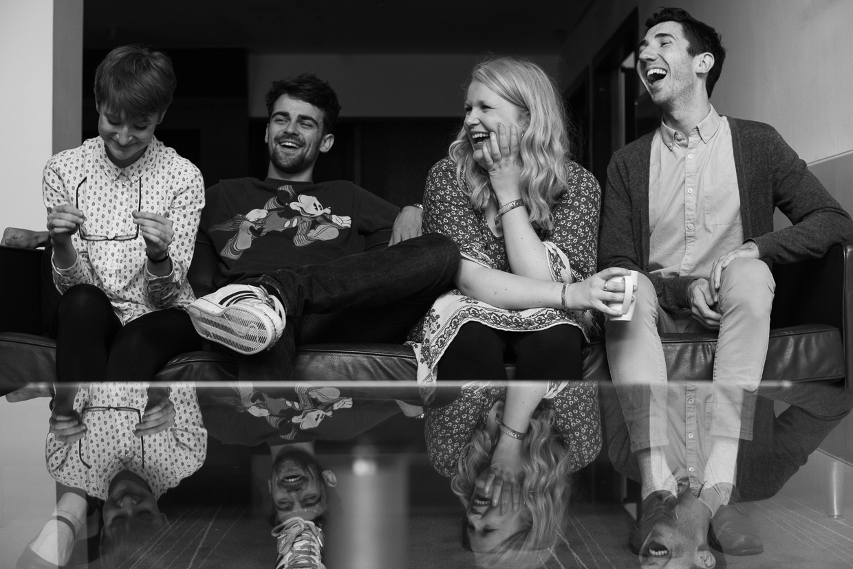 The cast sitting laughing in a sofa