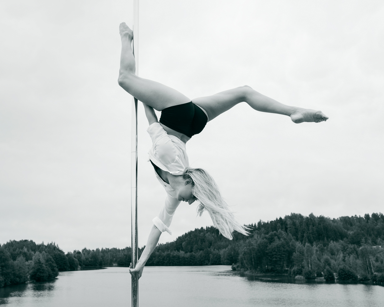 Helle Carlstedt doing a butterfly on the pole with the Blue Lagoon in the background.